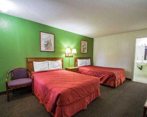 a hotel room with two beds and a chair at Rodeway Inn Fort Pierce I-95 in Fort Pierce