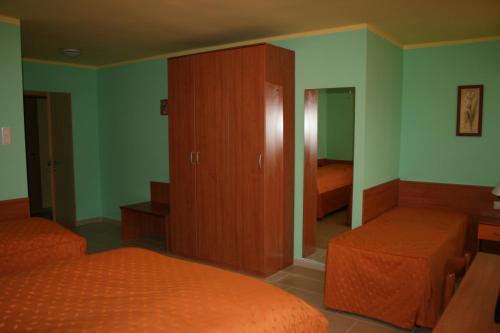 a bedroom with two beds and a cabinet and a mirror at Panoráma Panzió in Matrafured