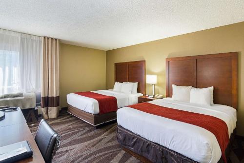 a hotel room with two beds and a desk at Comfort Inn Pensacola - University Area in Pensacola