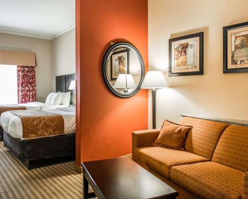 a hotel room with a bed and a couch and a mirror at Comfort Suites Panama City near Tyndall AFB in Panama City