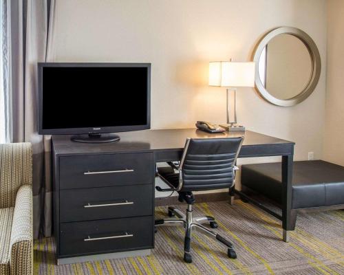 a desk with a television and a chair in a hotel room at Comfort Suites Miami Airport North in Miami