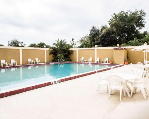a swimming pool with white chairs and tables and chairs at Quality Inn & Suites Winter Park Village Area in Orlando