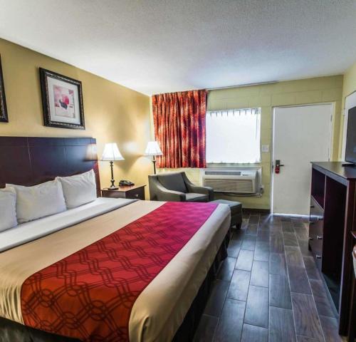a hotel room with a large bed and a chair at Econo Lodge Cocoa Beach - near the Port in Cocoa Beach