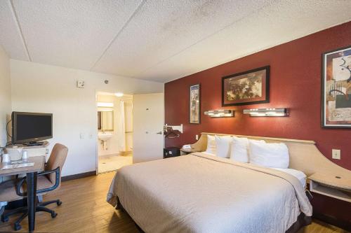 a hotel room with a bed and a desk and a television at Bay Inn in Tampa