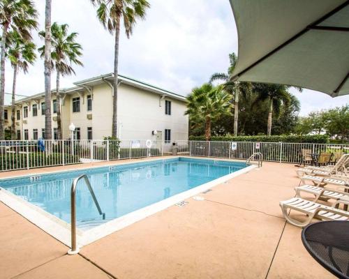 a swimming pool with chairs and a building at Sleep Inn at PGA Village in Port Saint Lucie