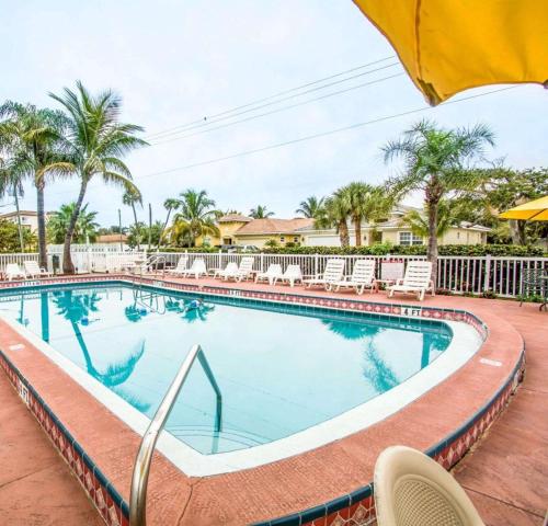a swimming pool at a resort with chairs and palm trees at Econo Lodge Cocoa Beach - near the Port in Cocoa Beach