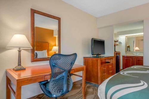 a hotel room with a desk and a bed and a mirror at Quality Inn Savannah Historic District in Savannah