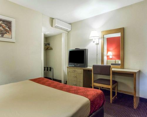 a hotel room with a bed and a desk and a television at Econo Lodge Atlanta College Park in Atlanta