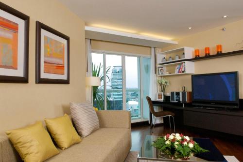 a living room with a couch and a desk with a television at The Narathiwas Hotel & Residence Sathorn Bangkok in Bangkok