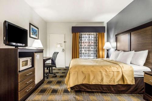 a hotel room with a bed and a flat screen tv at Quality Inn near Six Flags Douglasville in Douglasville