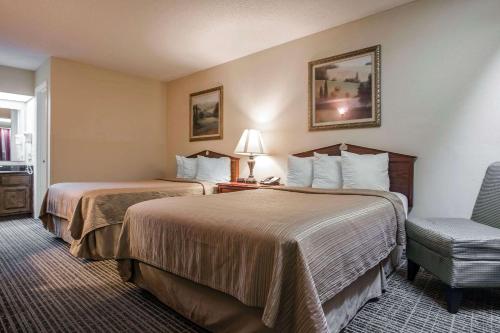 una habitación de hotel con 2 camas y una silla en Quality Inn Waynesboro, en Waynesboro