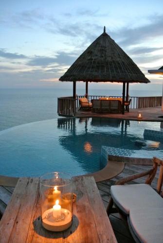 a candle on a wooden table next to a swimming pool at Villas Sabai Jai in Koh Tao