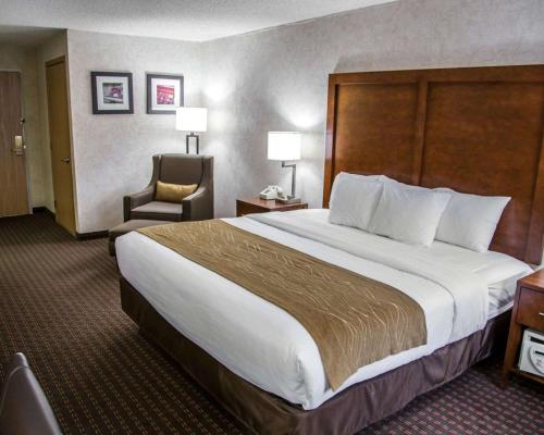 a hotel room with a large bed and a chair at Comfort Inn & Suites Riverview near Davenport and I-80 in Le Claire