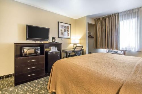 a hotel room with a bed and a flat screen tv at Quality Inn & Suites Decorah in Decorah