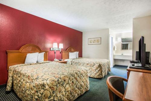 2 letti in una camera d'albergo con parete rossa di Rodeway Inn La Grange East a LaGrange