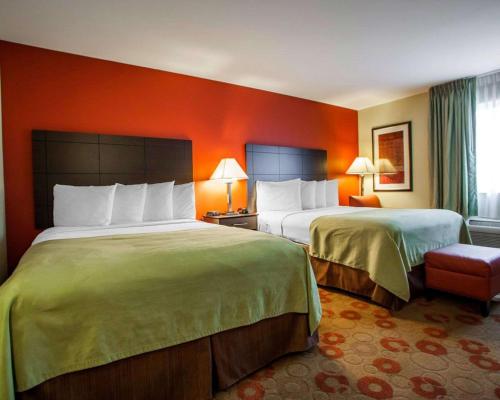 two beds in a hotel room with orange walls at Suburban Studios Cedar Falls in Cedar Falls