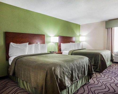 two beds in a hotel room with green walls at Quality Inn & Suites Altoona - Des Moines in Altoona