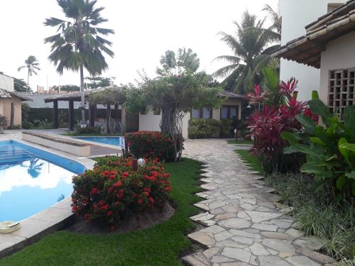 un patio del complejo con piscina y flores en Apartamento na praia de Taperapuan, en Porto Seguro