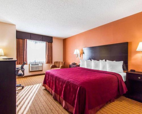 a hotel room with a large bed with a red blanket at Quality Inn & Suites Ottumwa North in Ottumwa