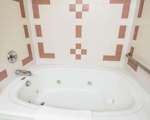a white bath tub in a bathroom with tiles at Quality Inn in Lewiston