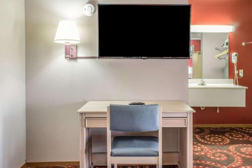 a desk with a chair and a tv on a wall at Spencer Inn & Suites in Spencer