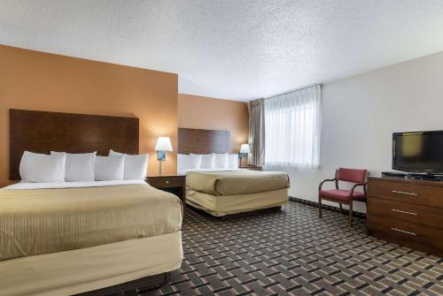 a hotel room with two beds and a flat screen tv at Quality Inn Osceola in Osceola