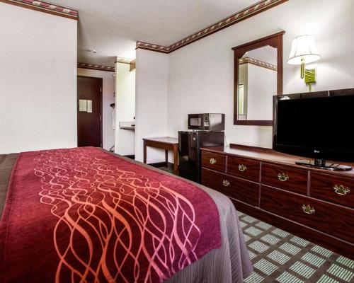 a hotel room with a bed and a flat screen tv at Quality Inn Arcola in Arcola