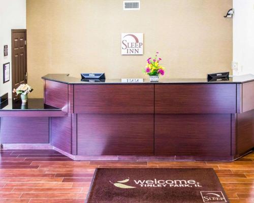 a wooden reception desk with flowers on top of it at Sleep Inn Tinley Park I-80 near Amphitheatre-Convention Center in Tinley Park