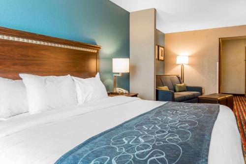 a hotel room with a large bed and a chair at Comfort Suites Fairview Heights Saint Louis in Fairview Heights