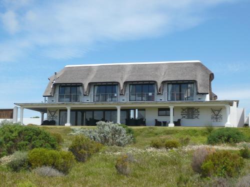 a house with a gambrel roof on top of a field at St Francis Golf Lodge in St Francis Bay