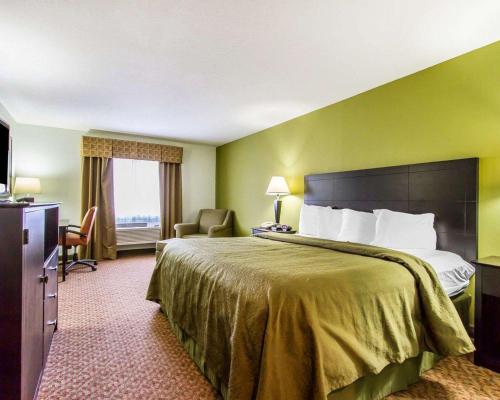 a hotel room with a large bed and a chair at Quality Inn in Pontiac