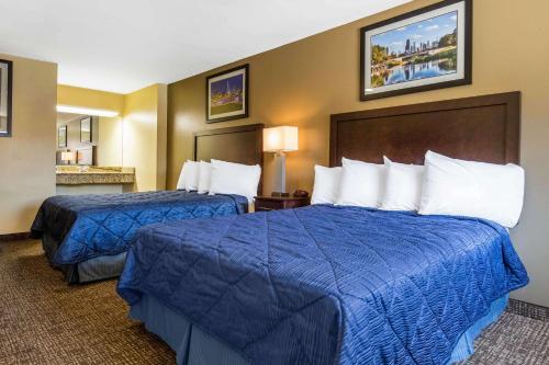 two beds in a hotel room with blue sheets at Rodeway Inn Lyons - La Grange in Lyons