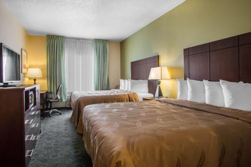 a hotel room with two beds and a flat screen tv at Quality Inn & Suites Bloomington I-55 and I-74 in Bloomington