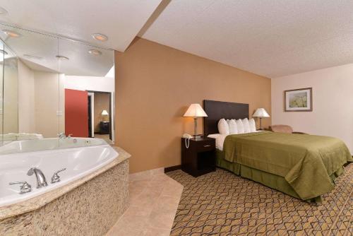 a hotel room with a bed and a bath tub at Quality Inn & Suites Matteson near I-57 in Matteson