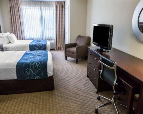 a hotel room with a bed and a desk with a tv at Comfort Suites University Area Notre Dame-South Bend in South Bend