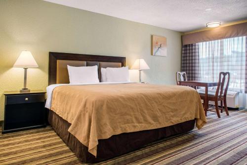 a hotel room with a bed with a desk and a table at Quality Inn in Huntingburg