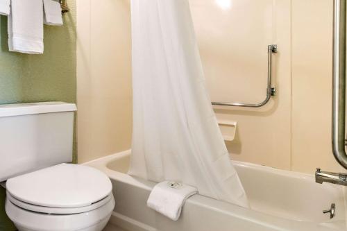 a bathroom with a toilet and a bathtub with a shower curtain at Quality Inn in Huntingburg