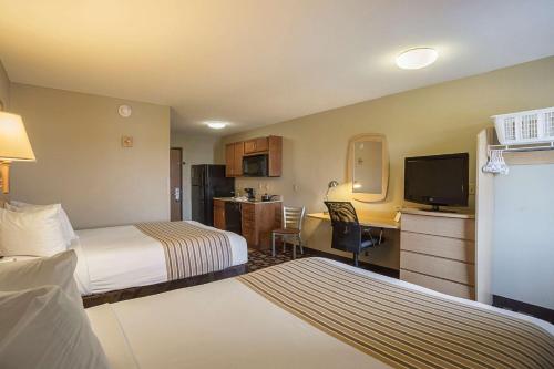 a hotel room with two beds and a flat screen tv at Suburban Studios Clarksville-Louisville North in Clarksville