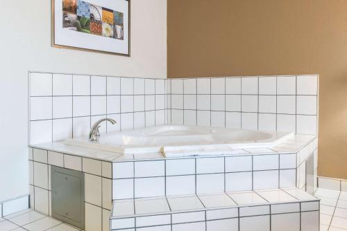 a bath tub in a white tiled bathroom at Quality Inn Noblesville-Indianapolis in Noblesville