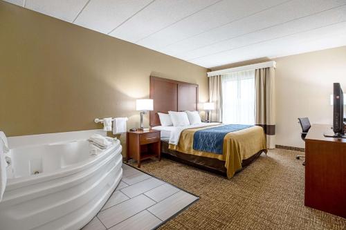 a hotel room with a bed and a bath tub at Comfort Inn Indianapolis North - Carmel in Carmel