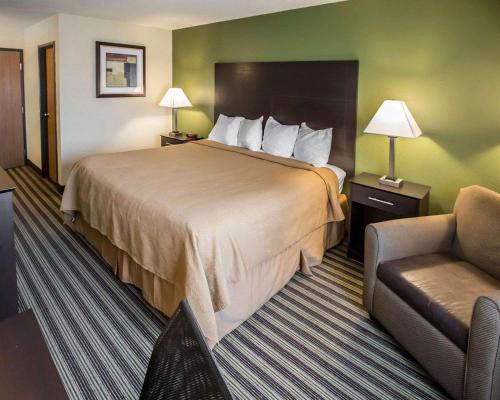 ein Hotelzimmer mit einem großen Bett und einem Stuhl in der Unterkunft Quality Inn Chesterton near Indiana Dunes National Park I-94 in Chesterton