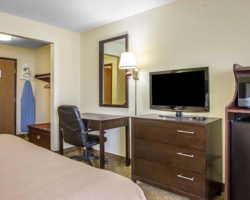 a hotel room with a bed and a desk with a television at Quality Inn Merrillville in Merrillville