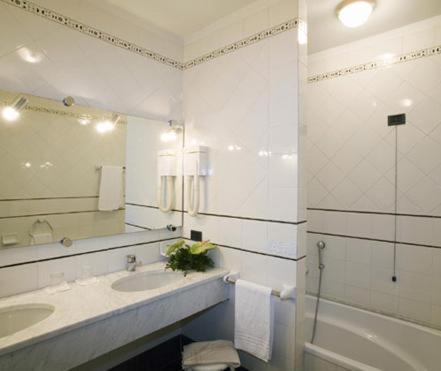 a bathroom with a sink and a tub and a mirror at Hotel Vittorio in Desenzano del Garda