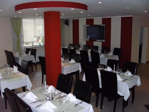 un comedor con mesas blancas y sillas negras en Hotel Adler, en Augsburg