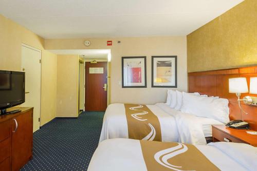 a hotel room with two beds and a flat screen tv at Quality Inn Boston-Revere in Revere