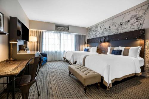 a hotel room with two beds and a table and chairs at enVision Hotel Boston-Everett in Boston
