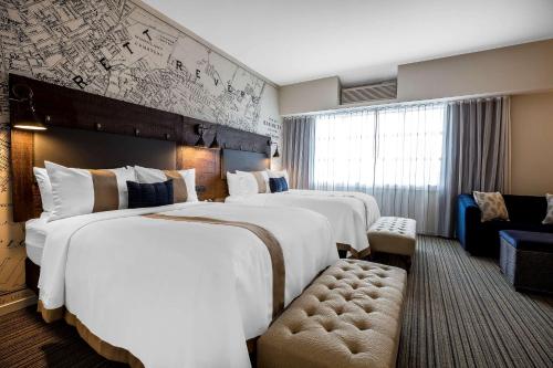 a hotel room with two beds and a couch at enVision Hotel Boston-Everett in Boston