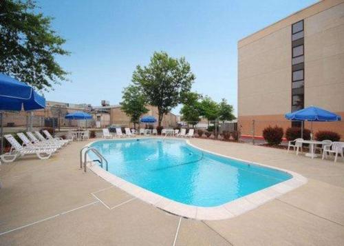 a pool with chairs and umbrellas next to a building at Comfort Inn Oxon Hill - National Harbor in Oxon Hill