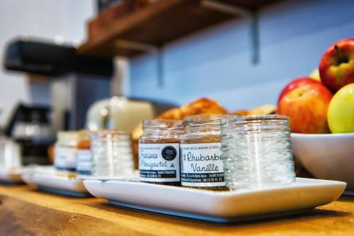 a table with jars of food and a bowl of apples at Hôtel Victor Hugo Lorient in Lorient