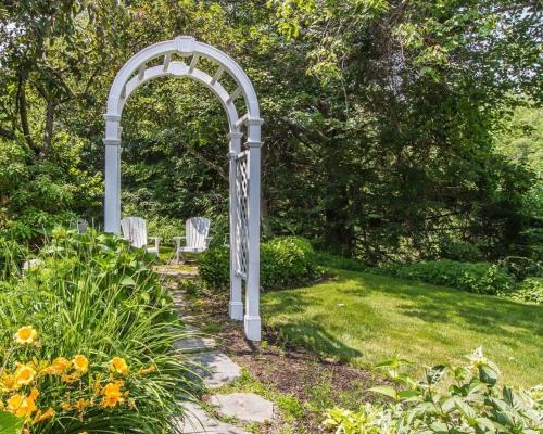 an arch in a garden with two white chairs at Comfort Inn Brunswick in Brunswick